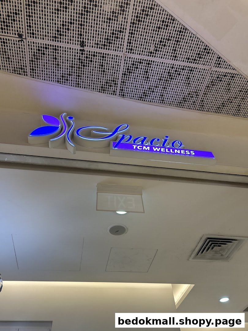 Illuminated 'Spacio TCM Wellness' sign above a shop entrance.