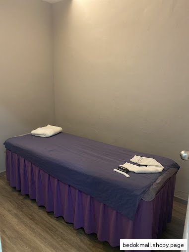 A treatment room with a massage bed and towels.