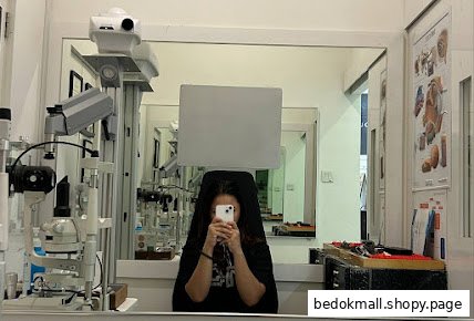 Interior of an optical shop with examination equipment and a person taking a photo.