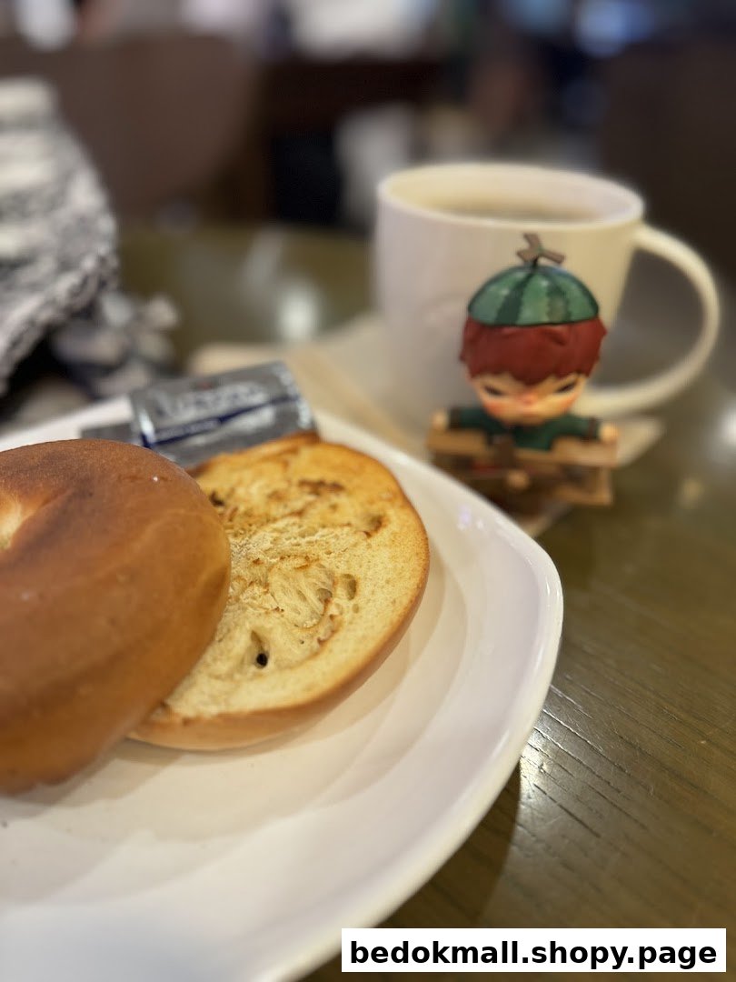 Bagel, butter, coffee cup, and figurine on a table.