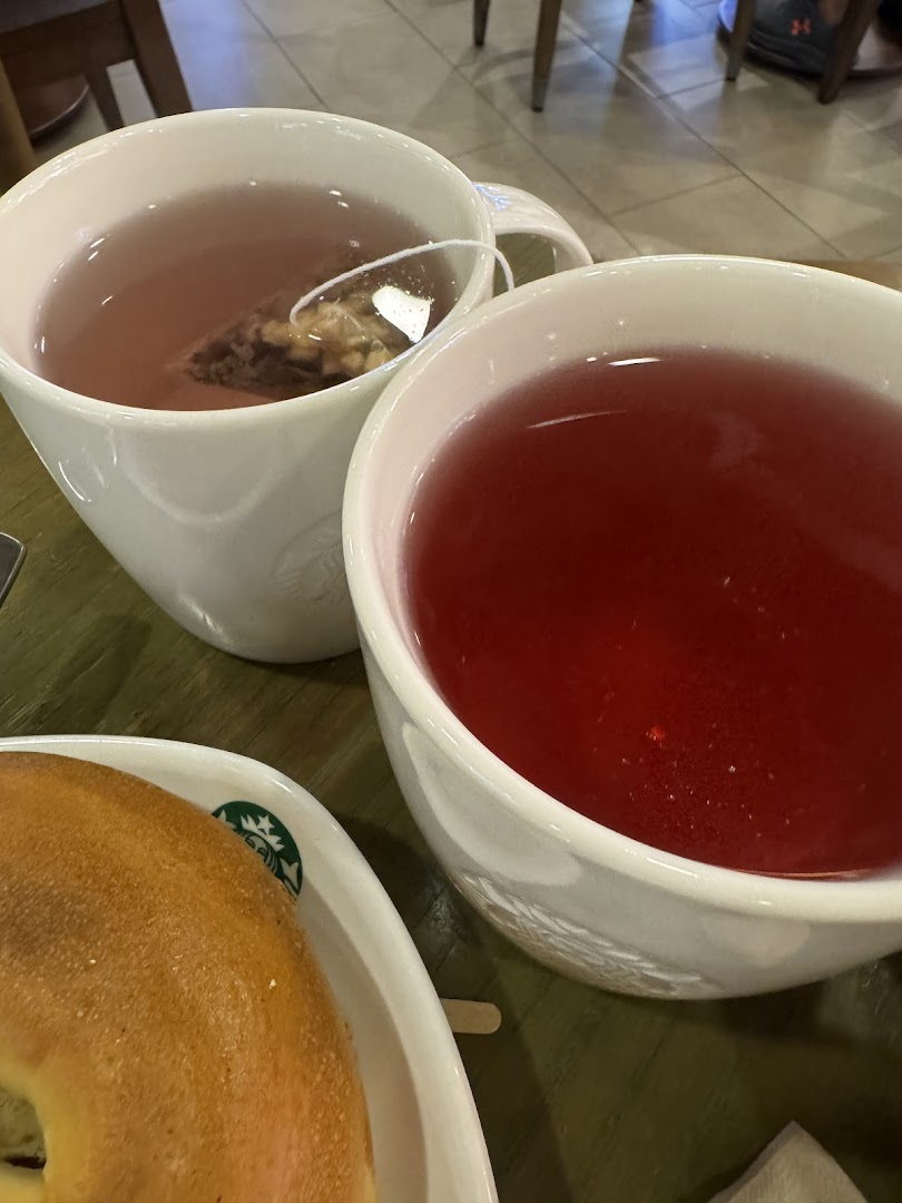 Two cups of tea and a bagel on a table at Starbucks.