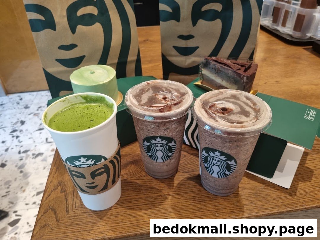 Starbucks drinks and cakes on a wooden table with branded bags.