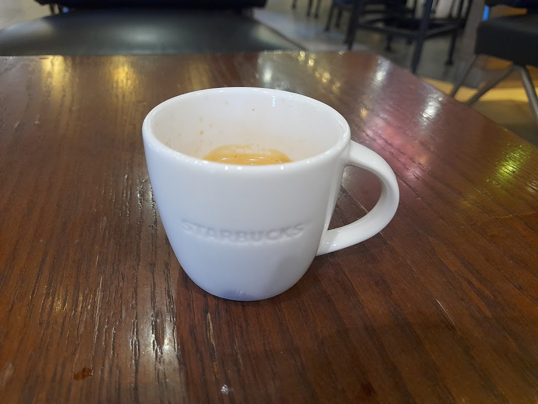 White Starbucks mug with coffee on a wooden table.