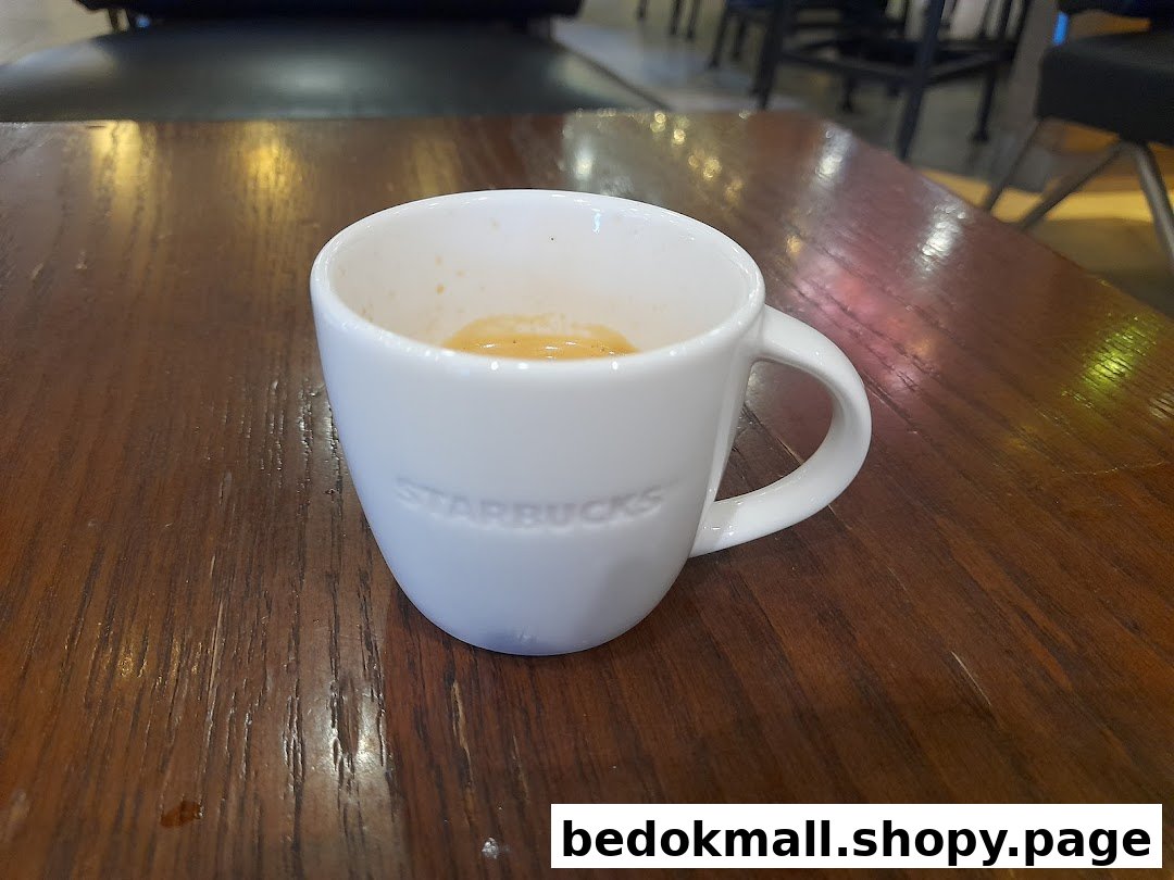 White Starbucks mug with coffee on a wooden table.