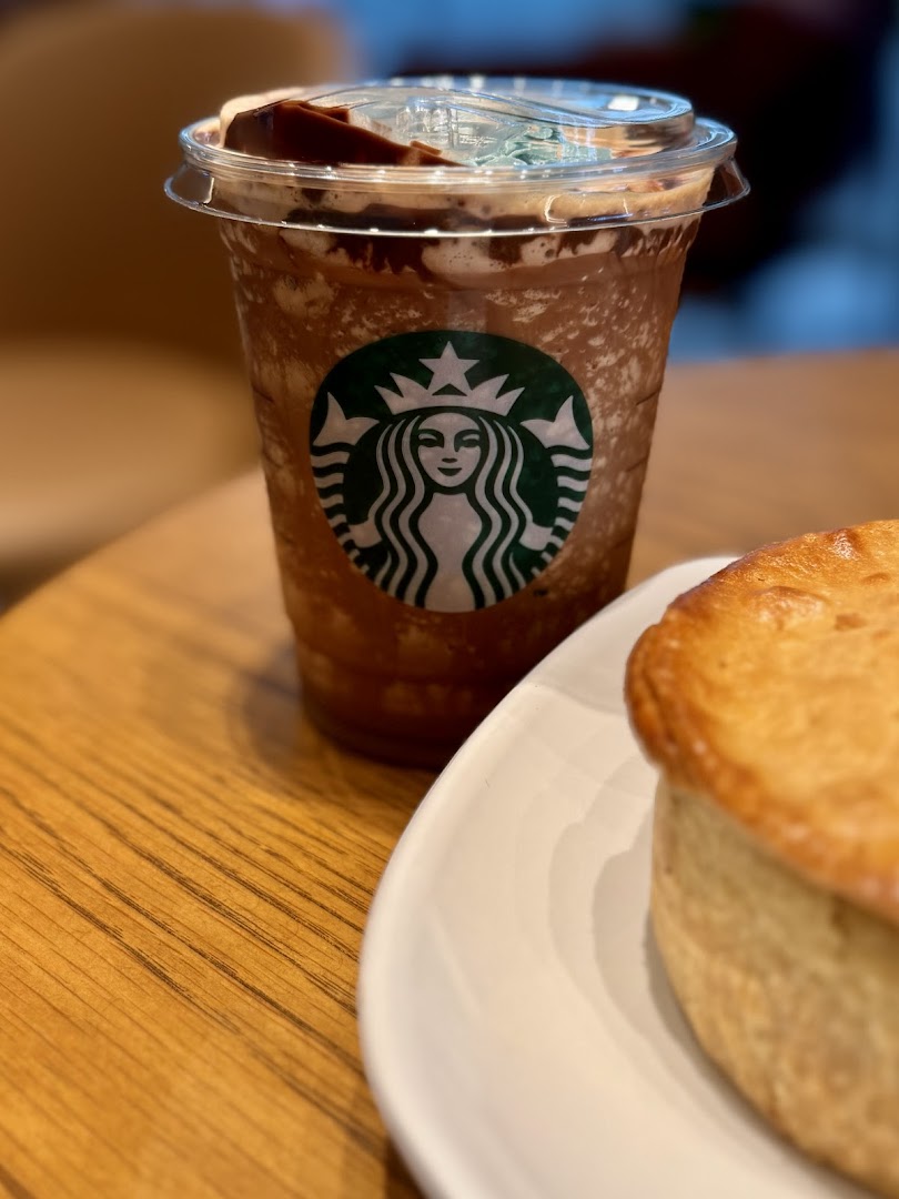A Starbucks Frappuccino and a pastry on a wooden table.