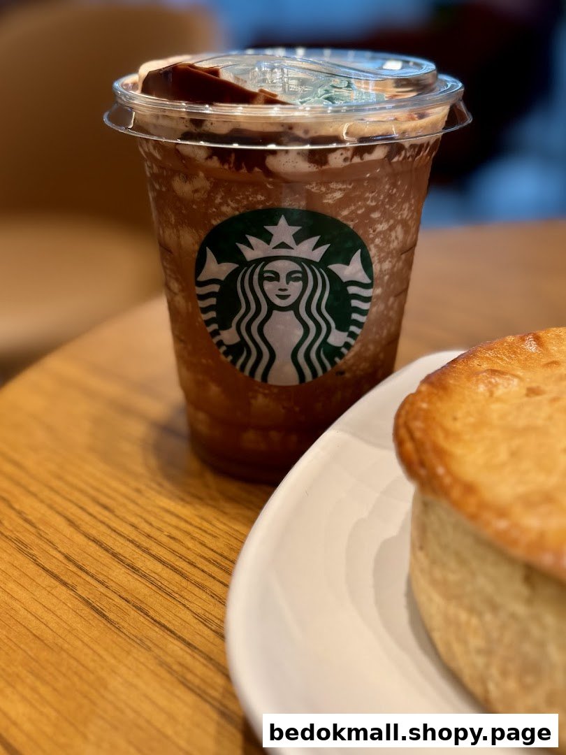 A Starbucks Frappuccino and a pastry on a wooden table.