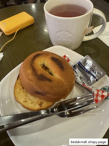 Bagel and tea served on a table with a Starbucks mug.