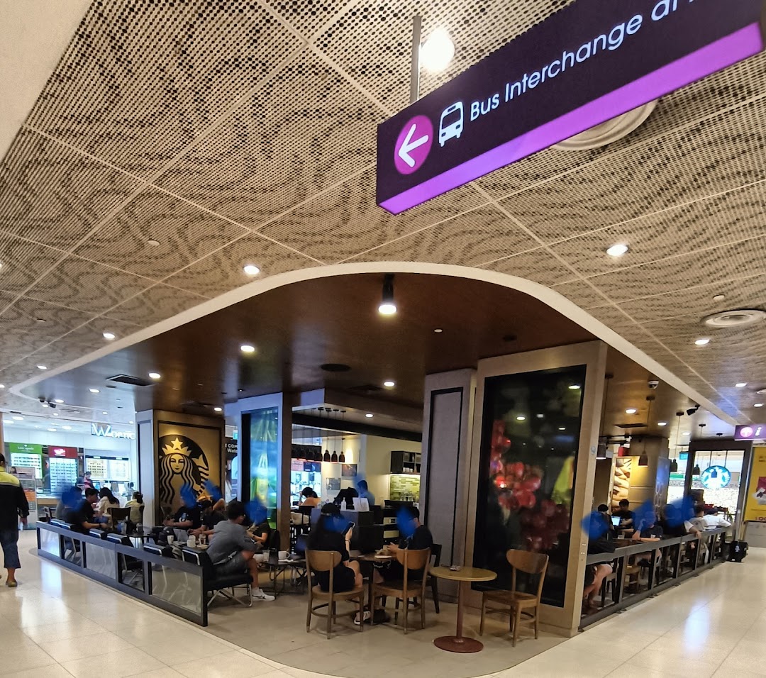 Interior view of a busy Starbucks cafe with customers and seating areas.
