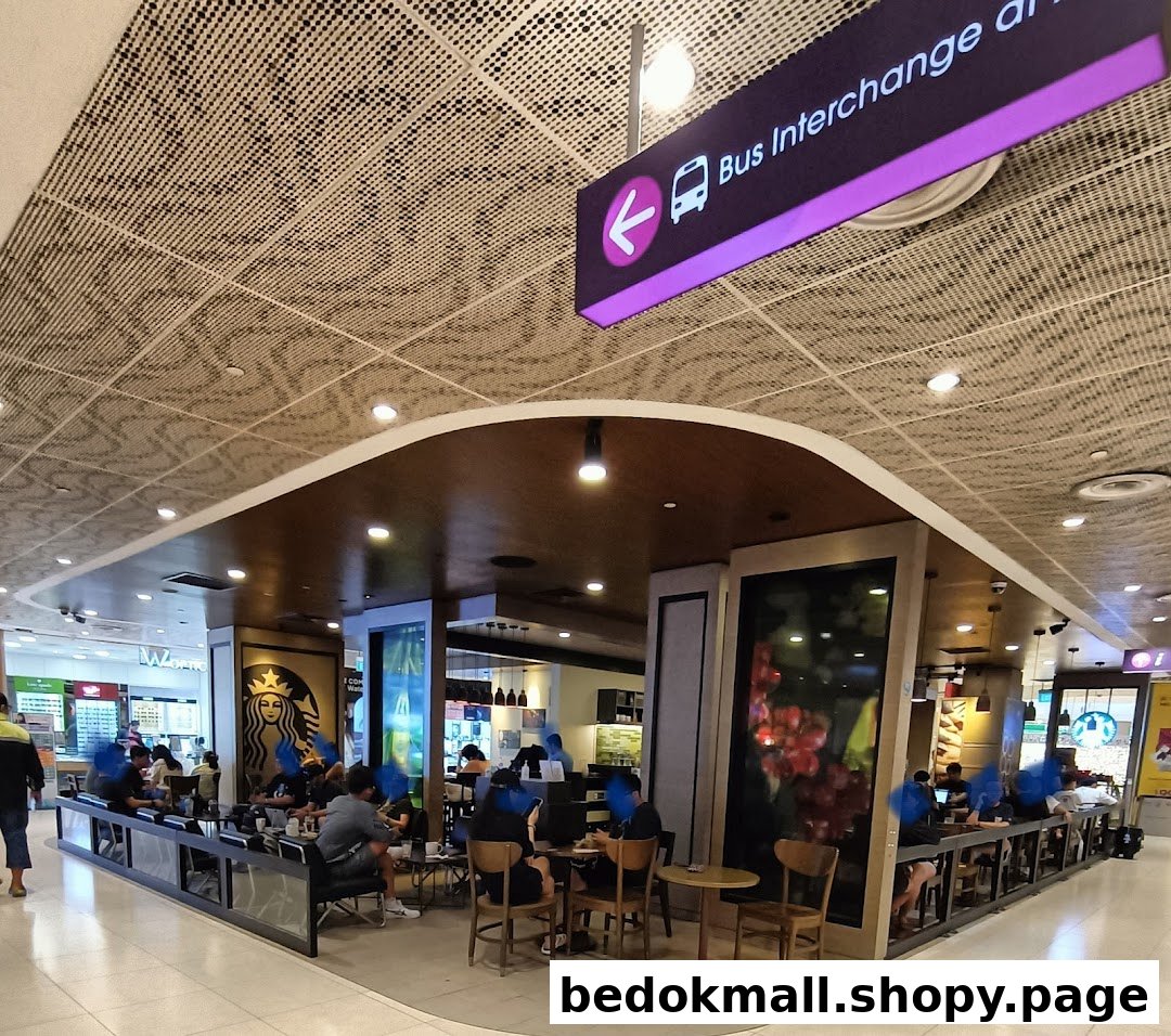 Interior view of a busy Starbucks cafe with customers and seating areas.