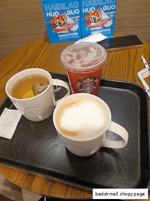 Three Starbucks drinks on a tray, including tea, coffee, and a cold beverage.