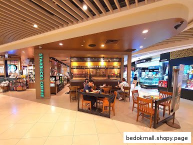 Starbucks coffee shop interior with seating area and customers in a mall.