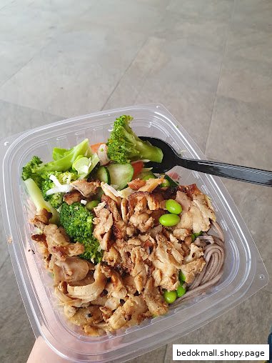 A plastic bowl of salad with chicken, broccoli, and noodles.