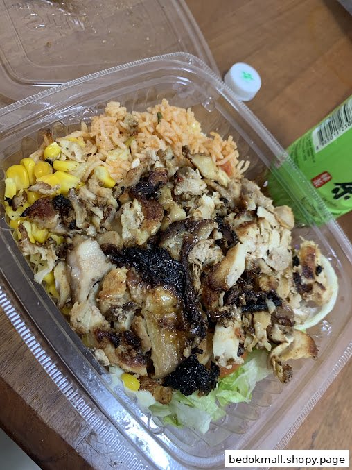 A plastic container with chopped chicken, rice, corn, and lettuce.