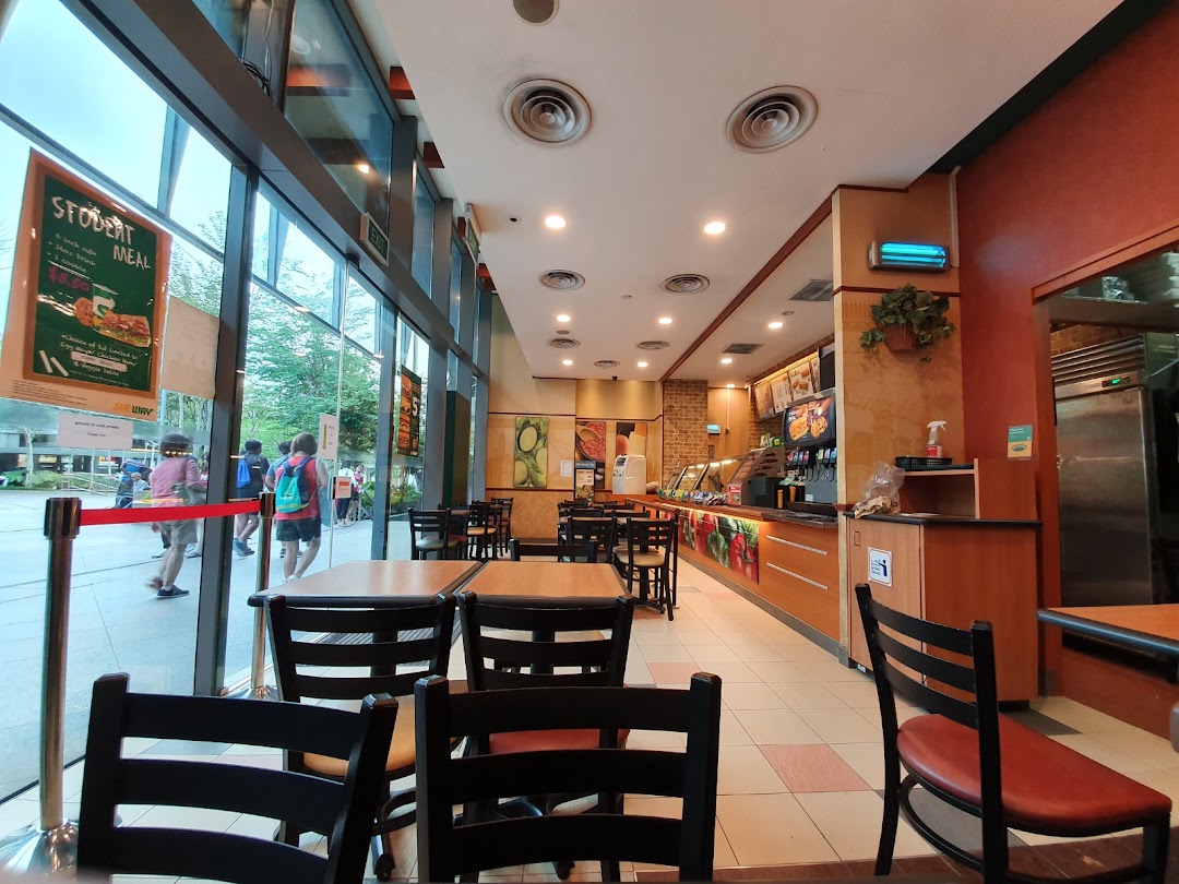 Interior view of a Subway restaurant with tables, service counter, and large windows.