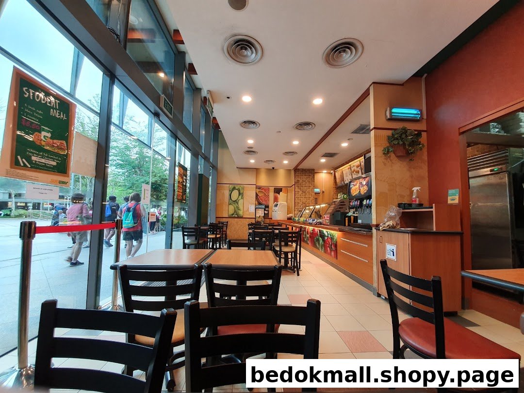 Interior view of a Subway restaurant with tables, service counter, and large windows.