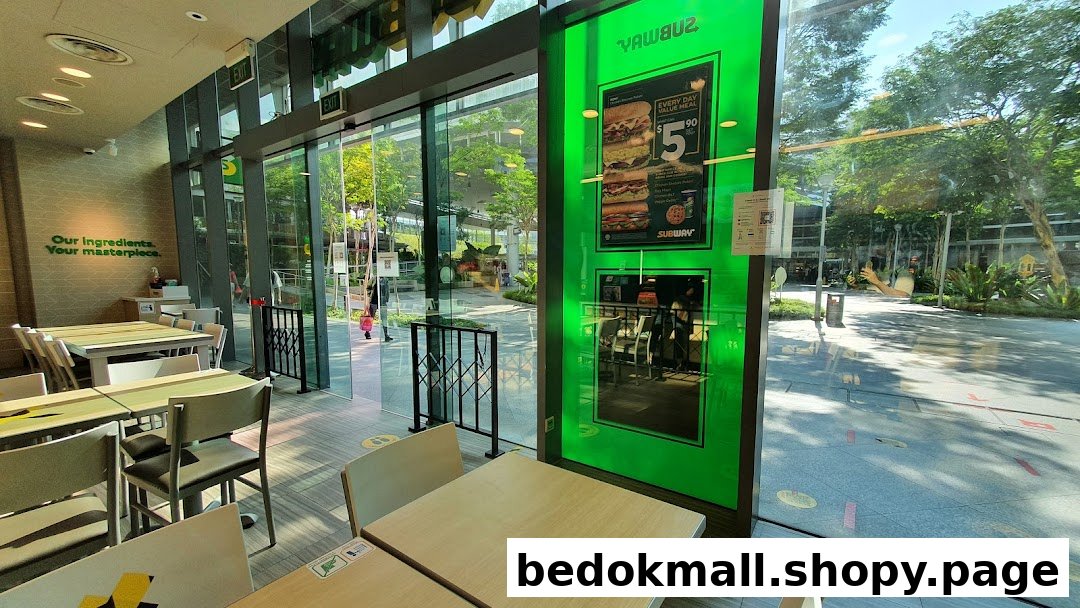 Interior view of a Subway restaurant with tables and large glass windows.