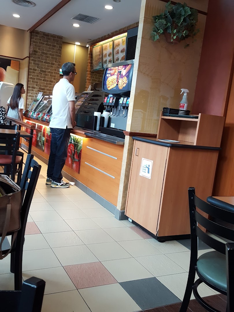 Interior view of a Subway restaurant with a customer at the counter.