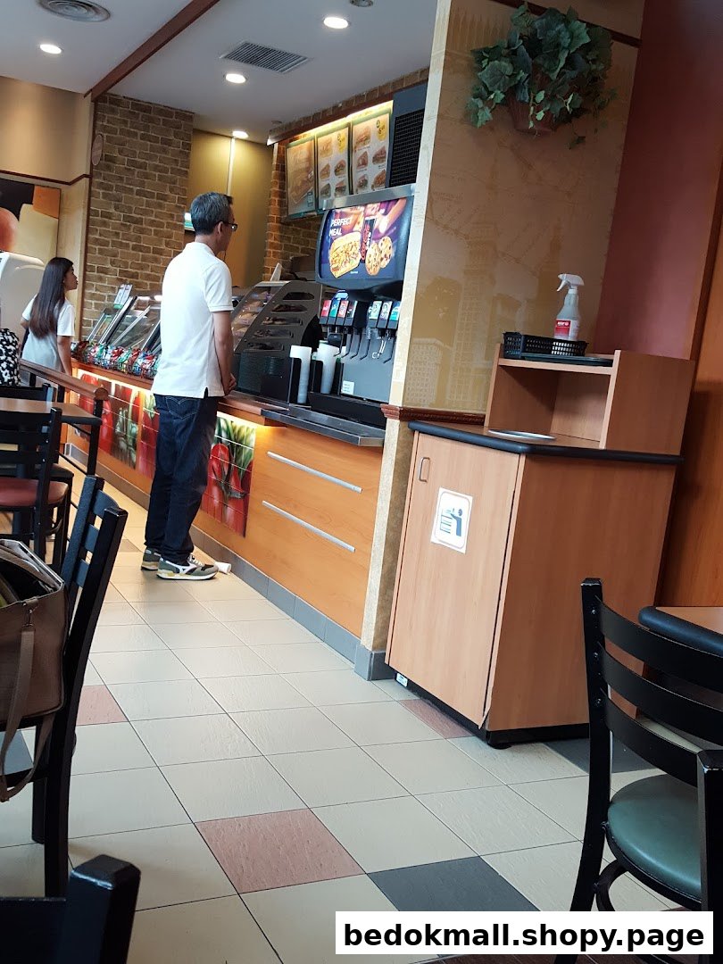 Interior view of a Subway restaurant with a customer at the counter.