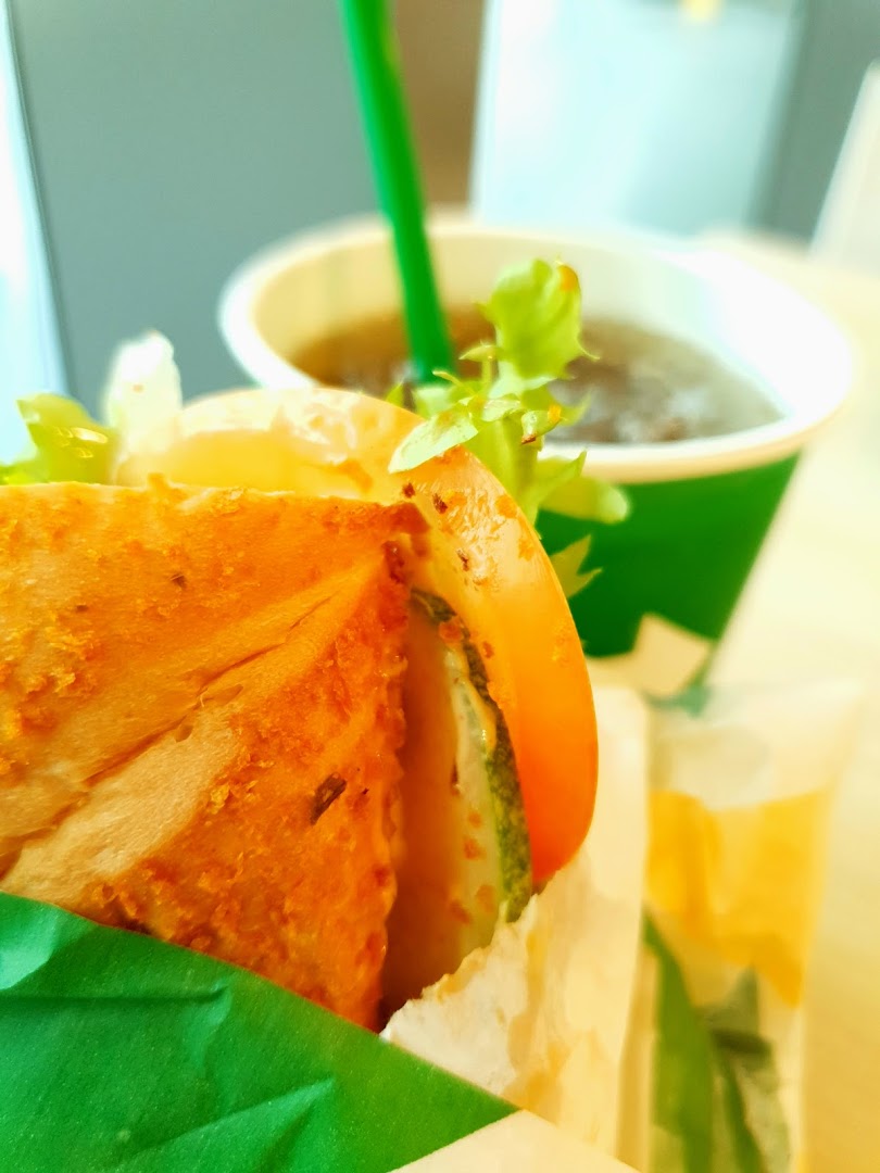 Close-up of a sandwich with vegetables and a drink in a cup.