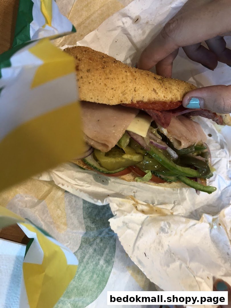 Hands holding a Subway sandwich with the wrapper visible.
