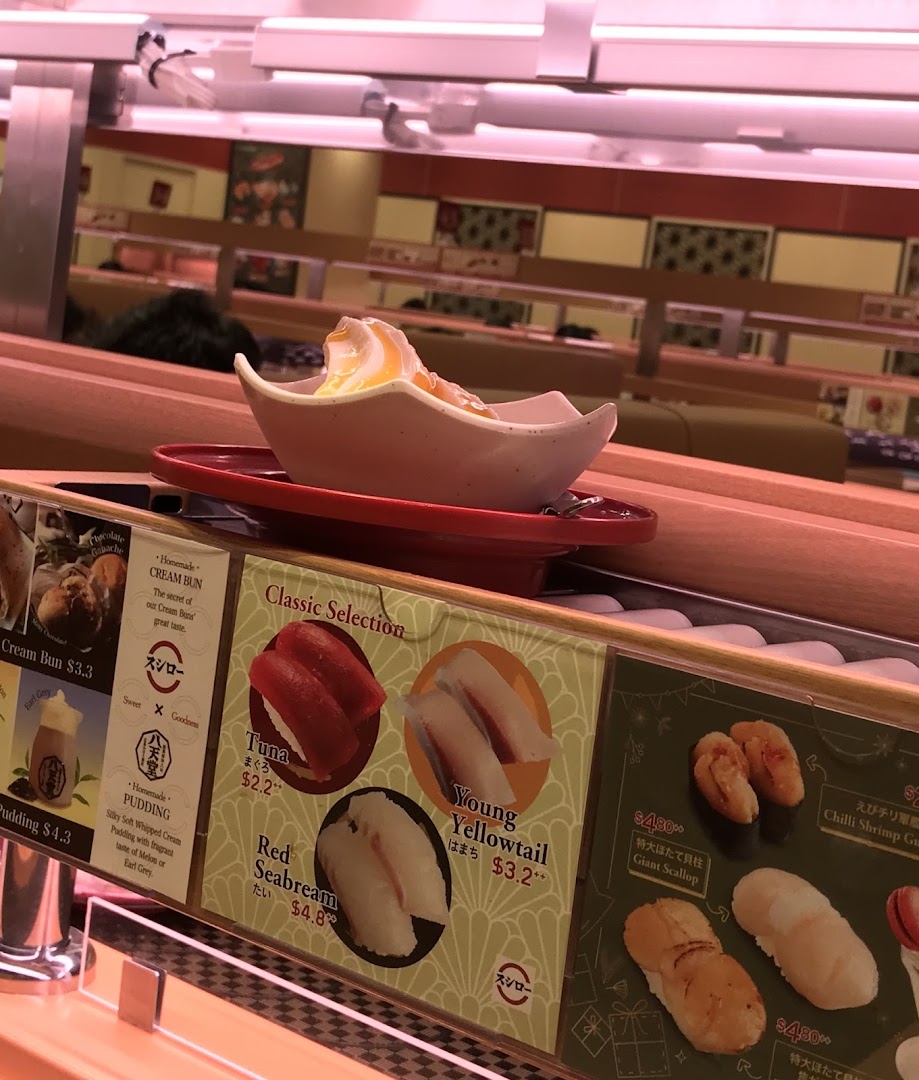 Conveyor belt sushi restaurant interior with food and menu displays.