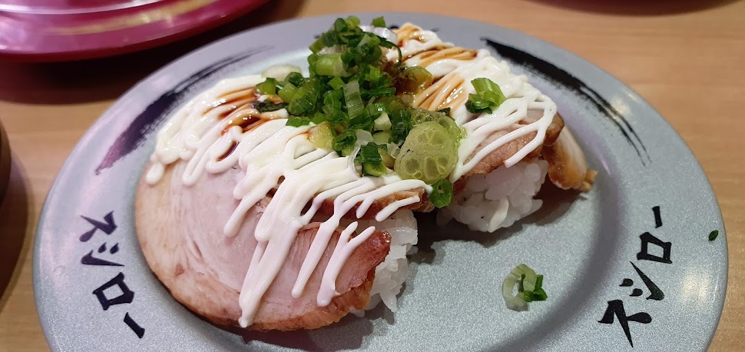 Close-up of sushi with meat, mayonnaise, and green onions on a plate.