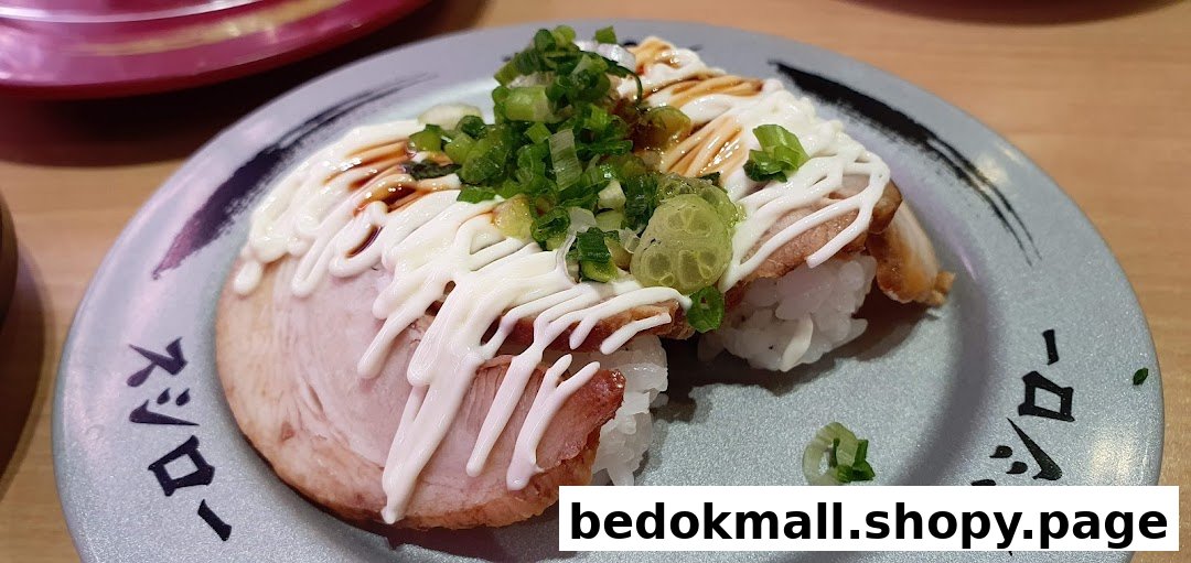 Close-up of sushi with meat, mayonnaise, and green onions on a plate.