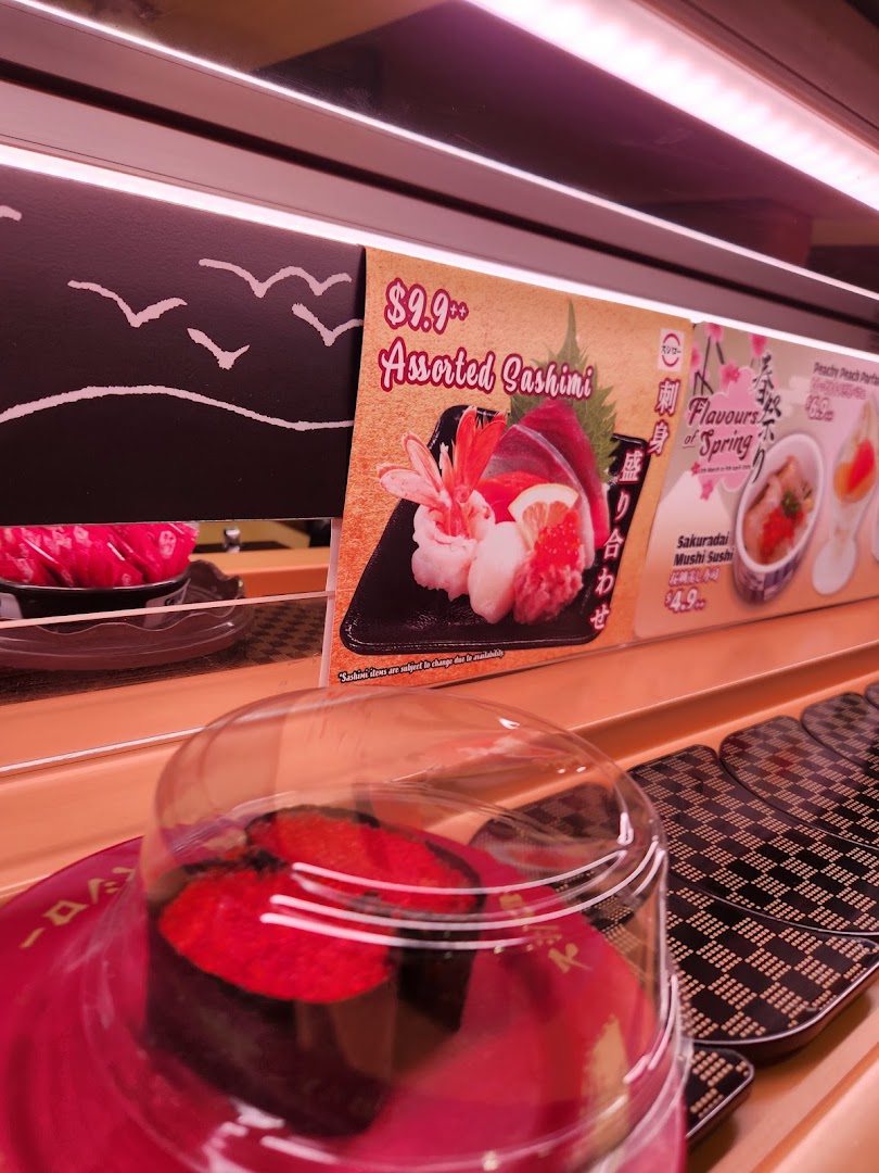 Sushi on a conveyor belt with menu displays in a restaurant.