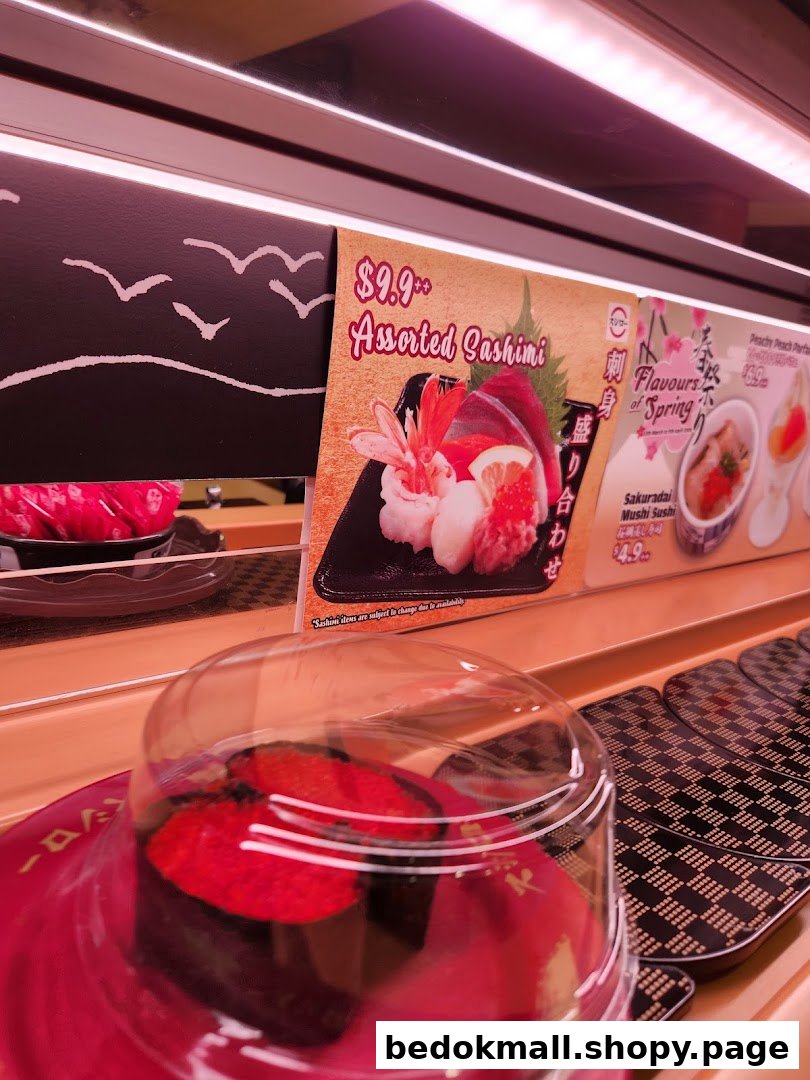 Sushi on a conveyor belt with menu displays in a restaurant.