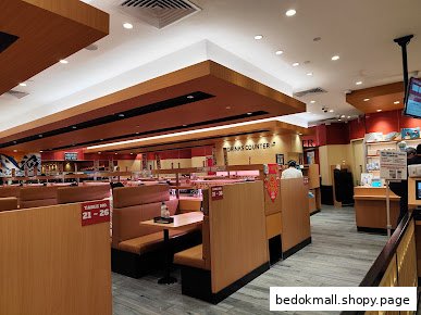 Interior of a sushi restaurant with conveyor belt and booth seating.