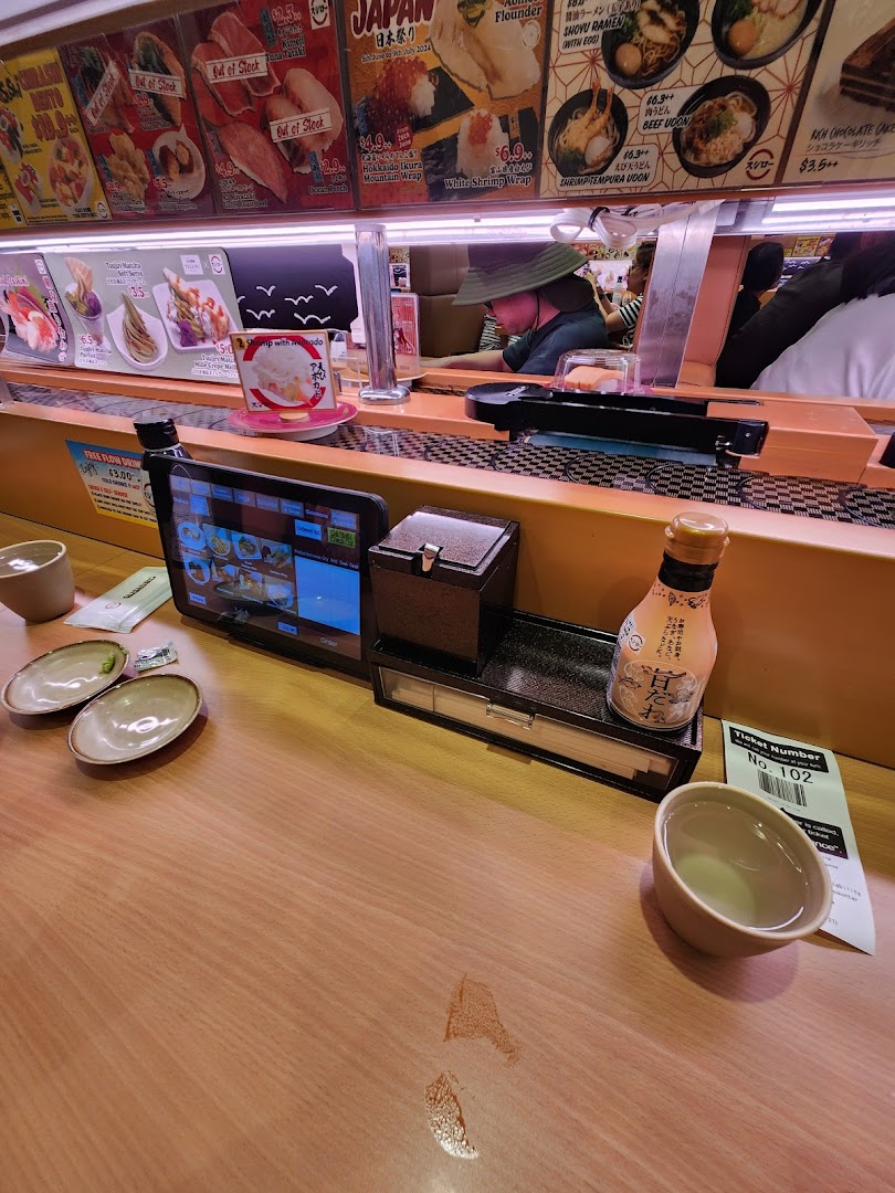 Interior of a sushi restaurant with a conveyor belt and ordering tablet.