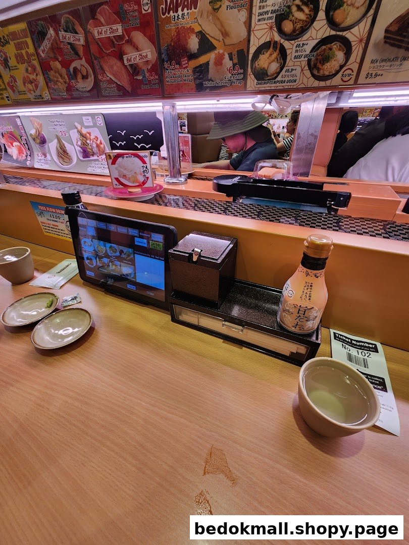 Interior of a sushi restaurant with a conveyor belt and ordering tablet.