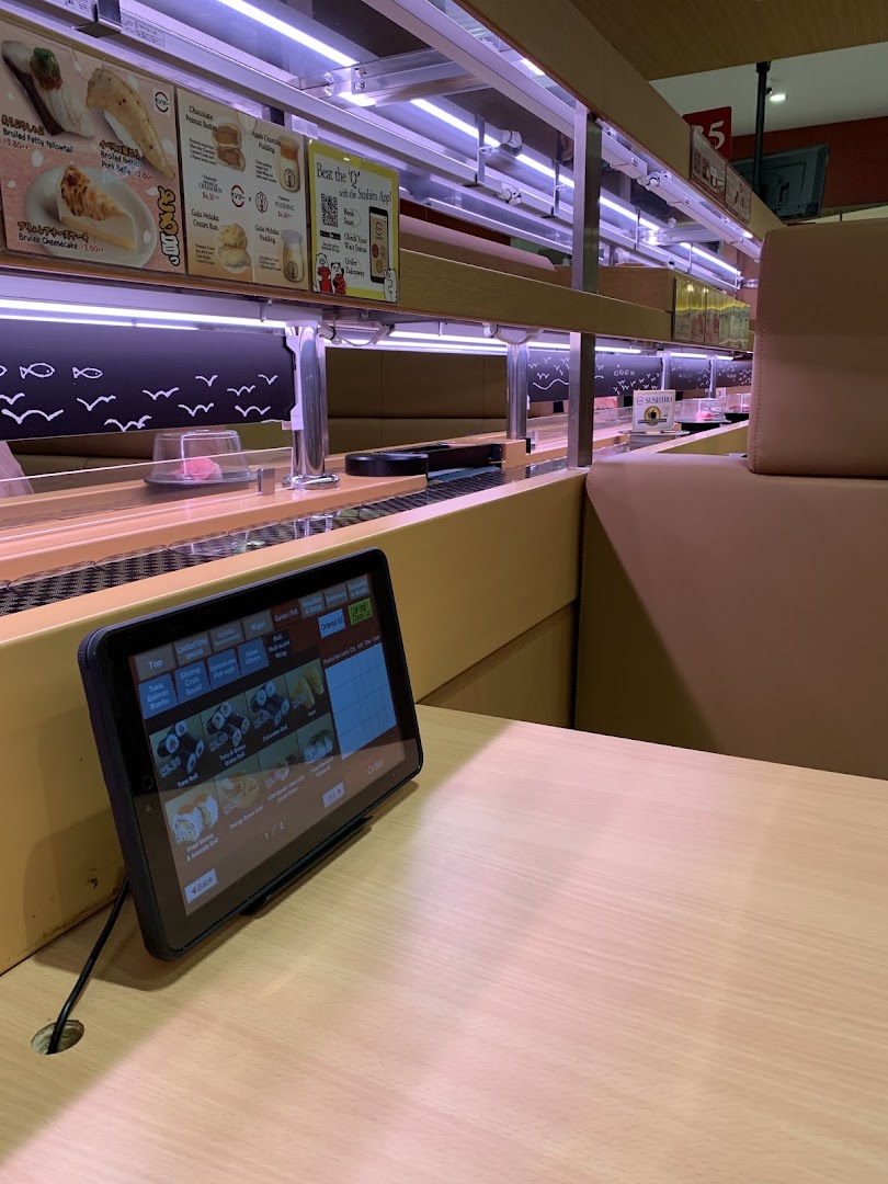 Interior view of a sushi restaurant with a conveyor belt and ordering tablet.