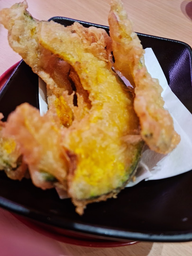 Golden tempura served in a black dish with white paper.