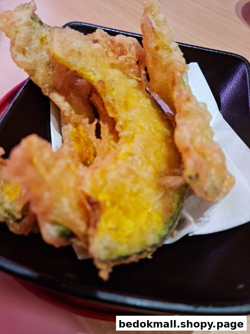 Golden tempura served in a black dish with white paper.