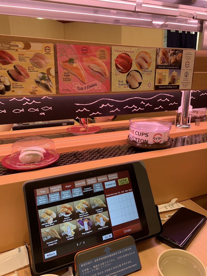 Interior of a sushi restaurant with a conveyor belt and ordering tablet.