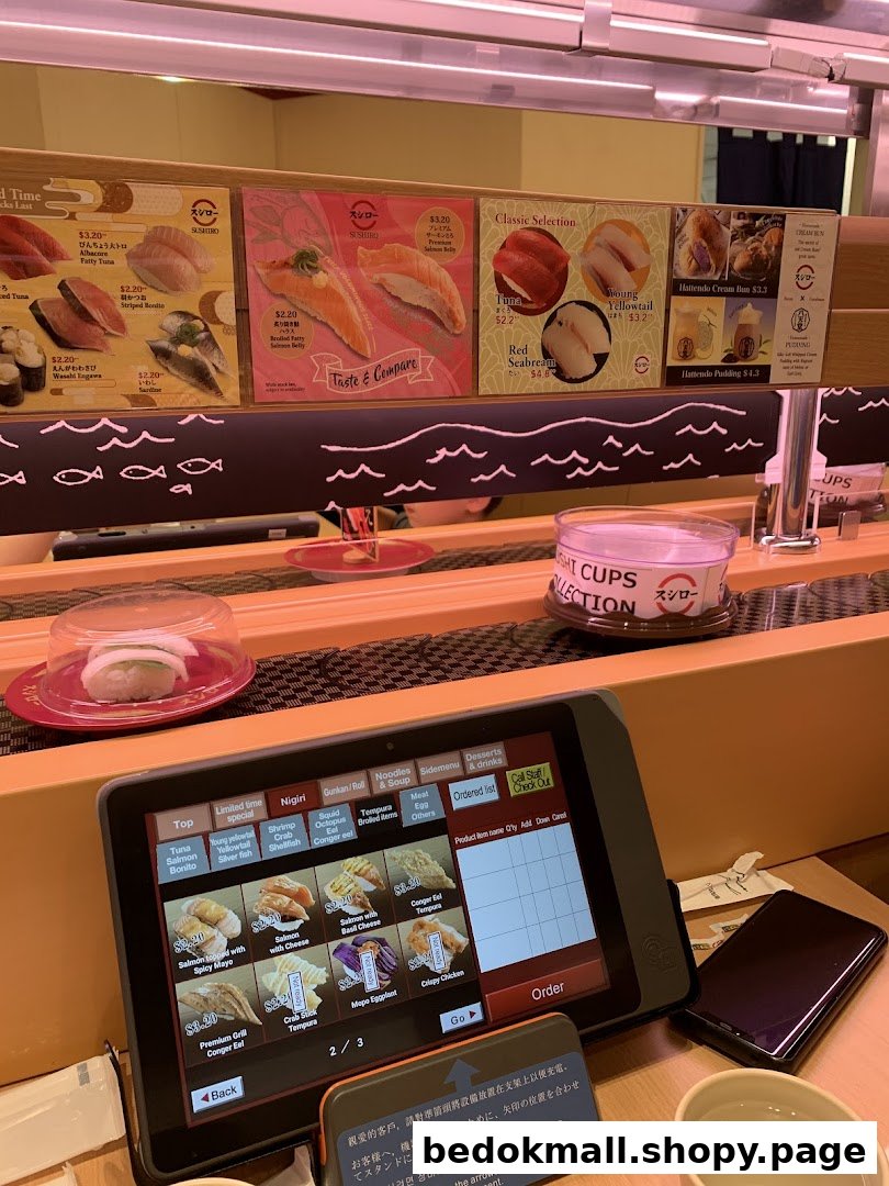 Interior of a sushi restaurant with a conveyor belt and ordering tablet.