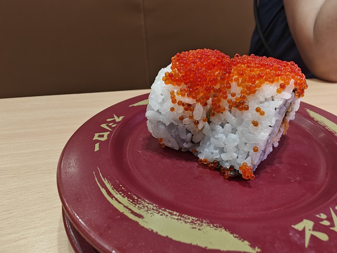 Close-up of a sushi roll topped with roe on a red plate.