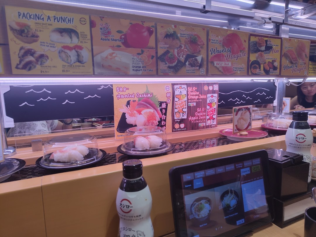 Sushi restaurant interior with conveyor belt, food, and overhead menu displays.