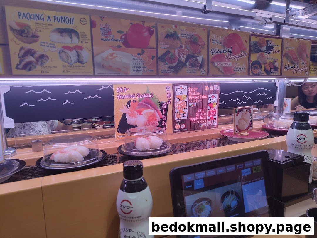 Sushi restaurant interior with conveyor belt, food, and overhead menu displays.