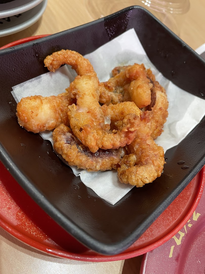 Close-up of golden fried calamari or octopus in a black bowl.
