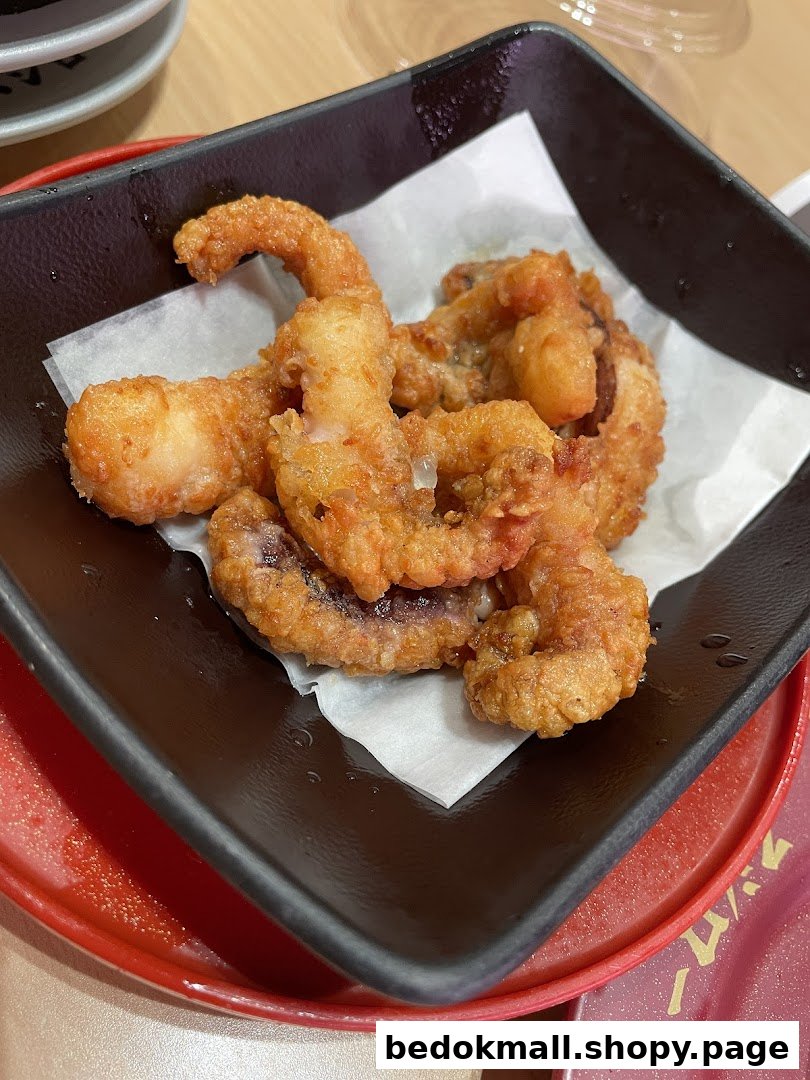 Close-up of golden fried calamari or octopus in a black bowl.