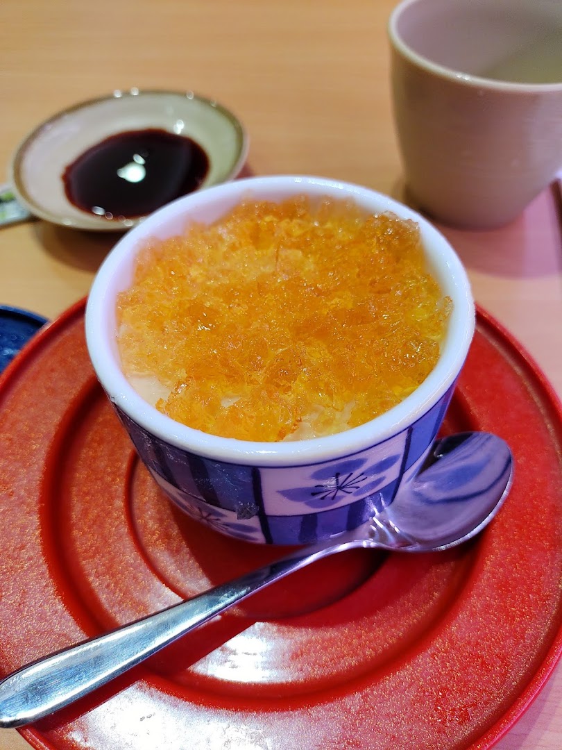 Close-up of a dessert or chawanmushi with orange topping on a red plate.