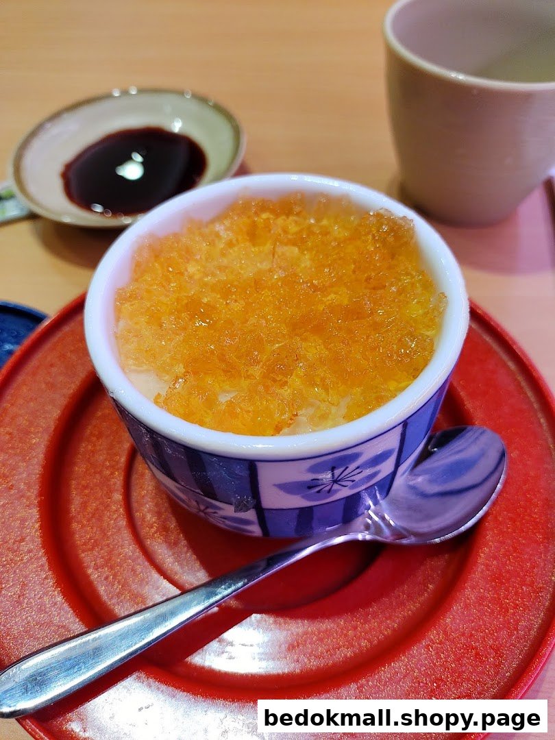 Close-up of a dessert or chawanmushi with orange topping on a red plate.