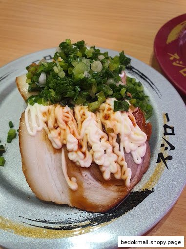 Close-up of a pork belly dish with mayonnaise and green onions on a plate.