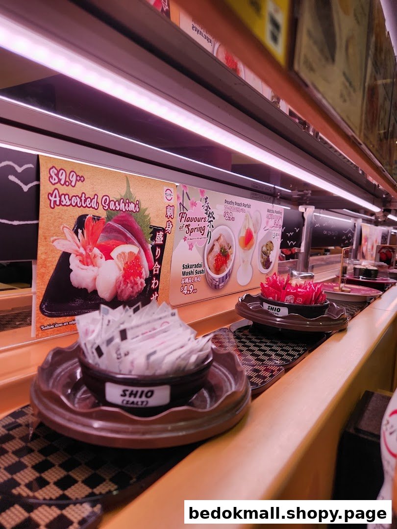 Interior view of a sushi restaurant with a conveyor belt and promotional posters.