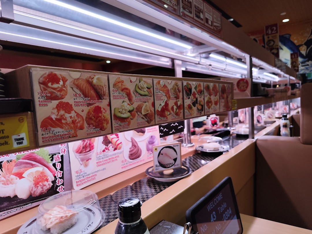 Interior view of a sushi restaurant with a conveyor belt and food displays.