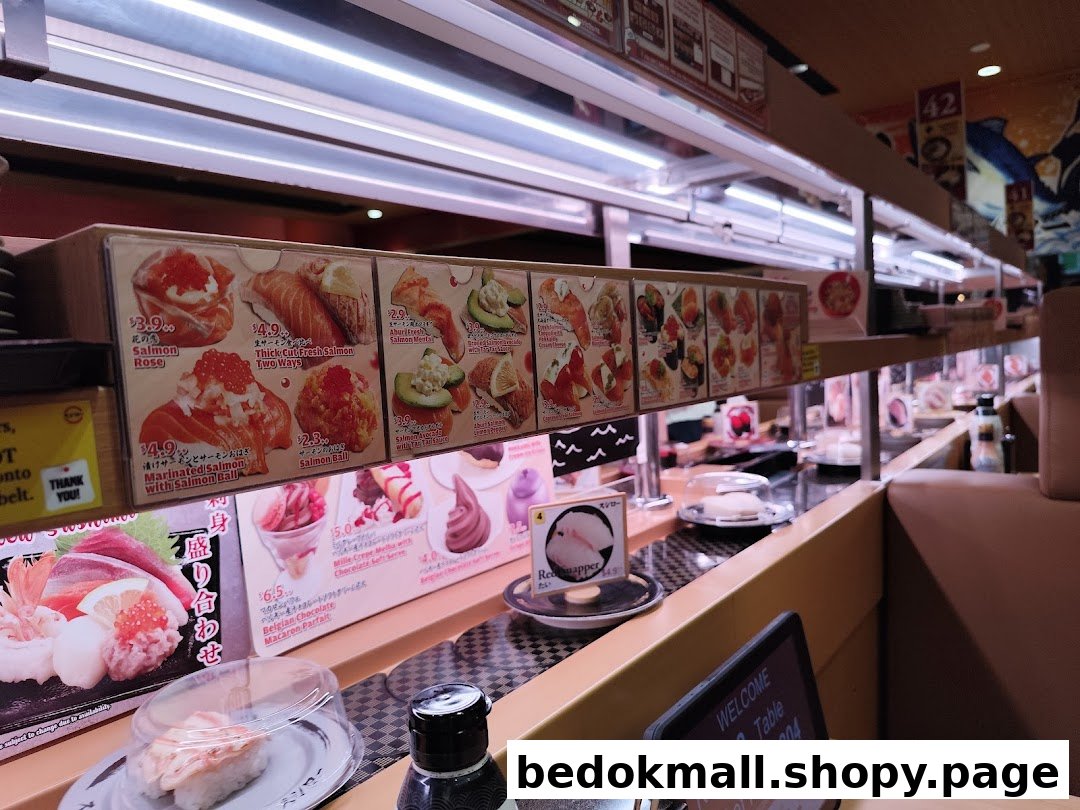 Interior view of a sushi restaurant with a conveyor belt and food displays.