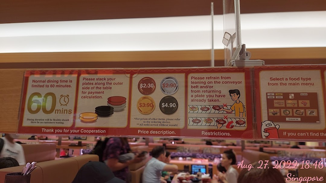 A sign displaying dining rules and plate prices in a sushi restaurant.