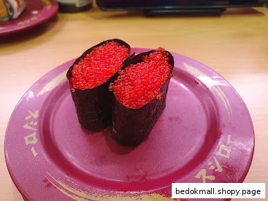 Two sushi pieces with red roe on a purple plate.
